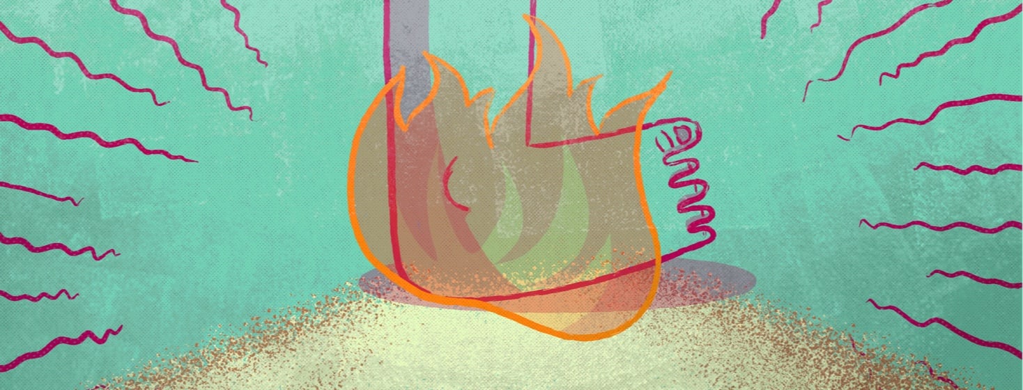 a foot stepping on a pile of sand with a fire around it.