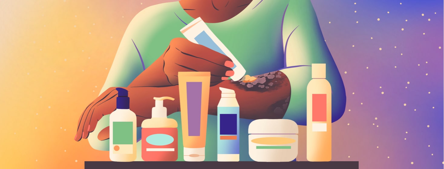 alt=a person applies a topical cream to their psoriasis plaques. An array of skincare products are arranged before them.