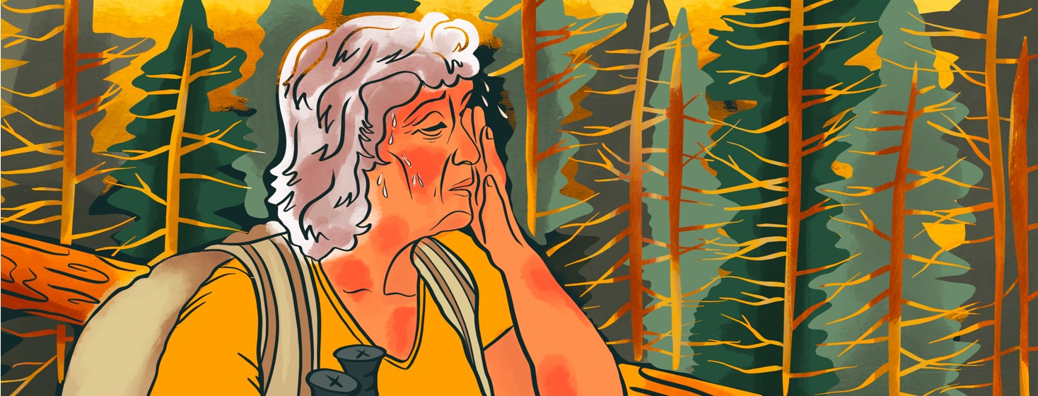 alt=An older woman hikes through the forest, wiping sweat from her brow. Her skin flares from the impact of summer heat.